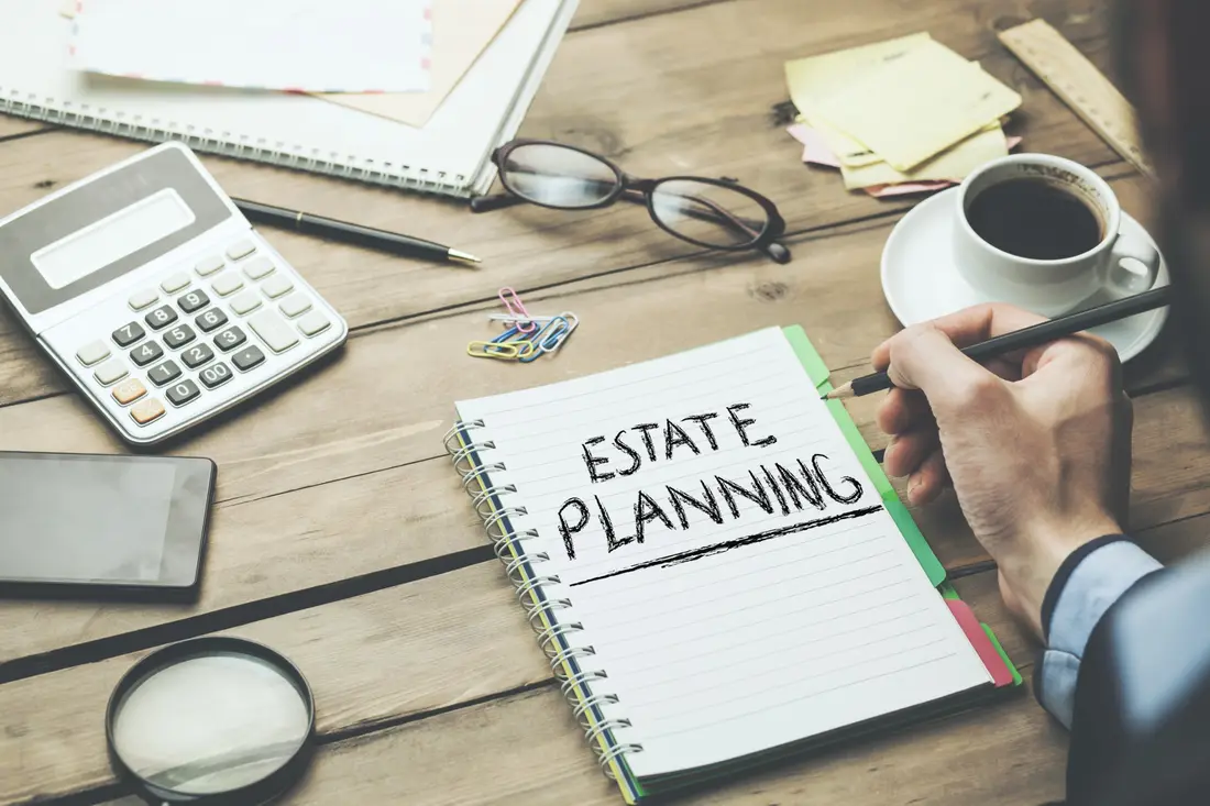 Notebook reading estate planning on a desk with a calculator and coffee