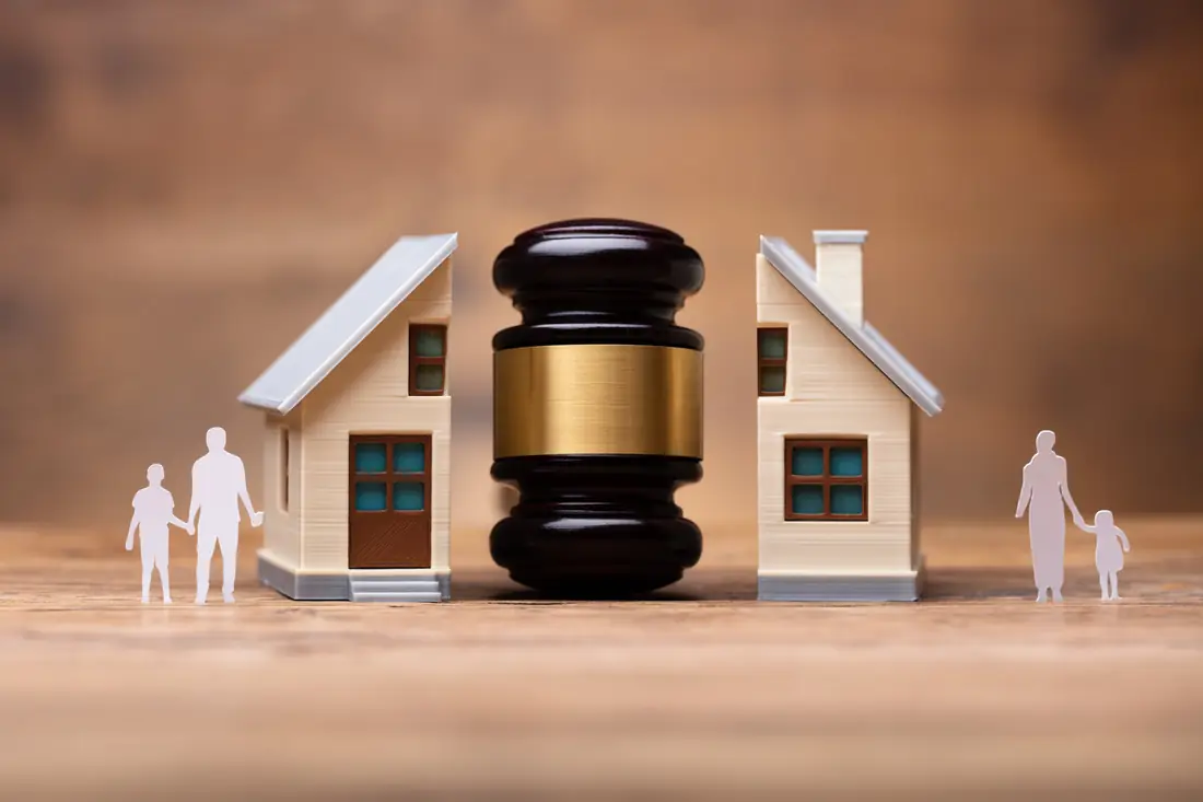 Two model houses divided by a gavel with a parent and child beside each