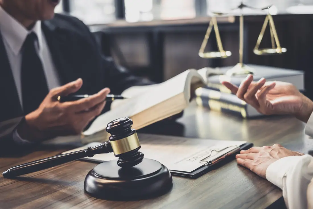 Solicitor advising a client across a desk with a gavel and scales